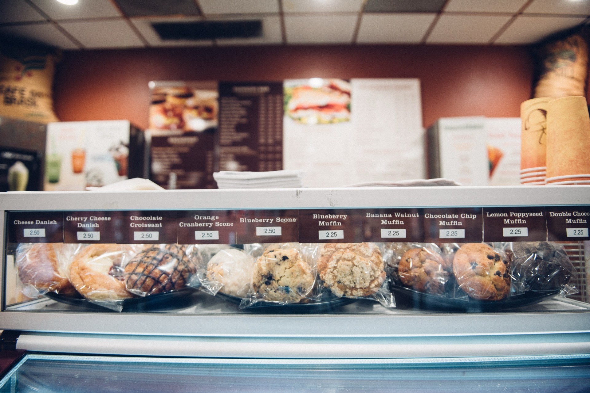 Full pastry display case with muffins, scones, and danishes